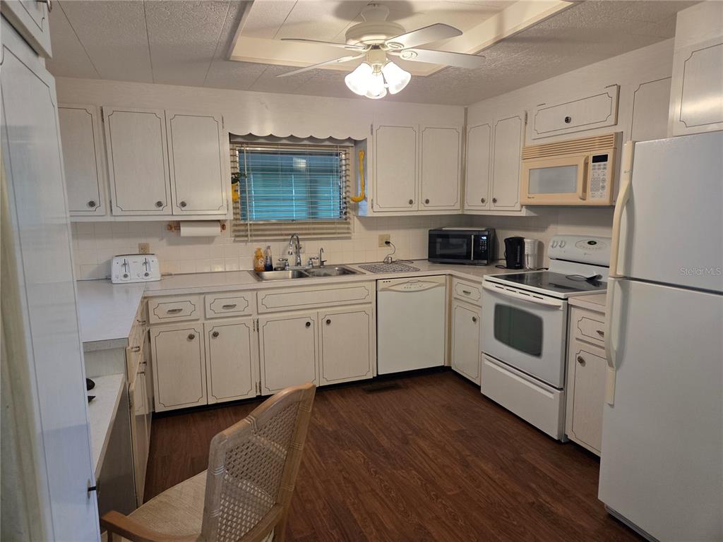 A kitchen features white cabinetry, white appliances, a ceiling fan, and wood-look flooring — 9900 ULMERTON ROAD UNIT 13, LARGO, FL