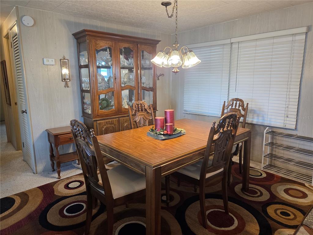 A dining room features a wooden table and chairs, a china cabinet, and a patterned rug — 9900 ULMERTON ROAD UNIT 13, LARGO, FL