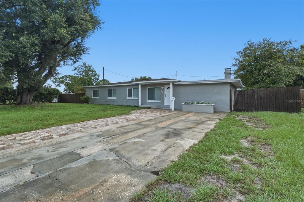 A single-story gray house features a concrete driveway, a paver walkway, and a large tree — 55 RANDIA DRIVE, ORLANDO, FL