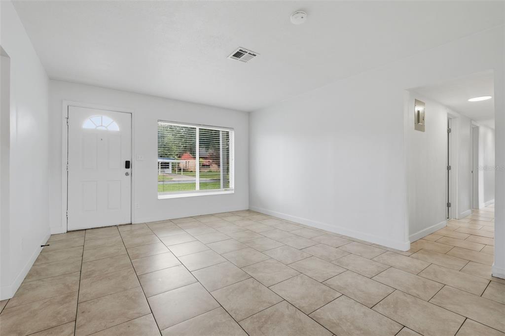 An empty room with white walls, tiled flooring, a front door, and a large window — 55 RANDIA DRIVE, ORLANDO, FL