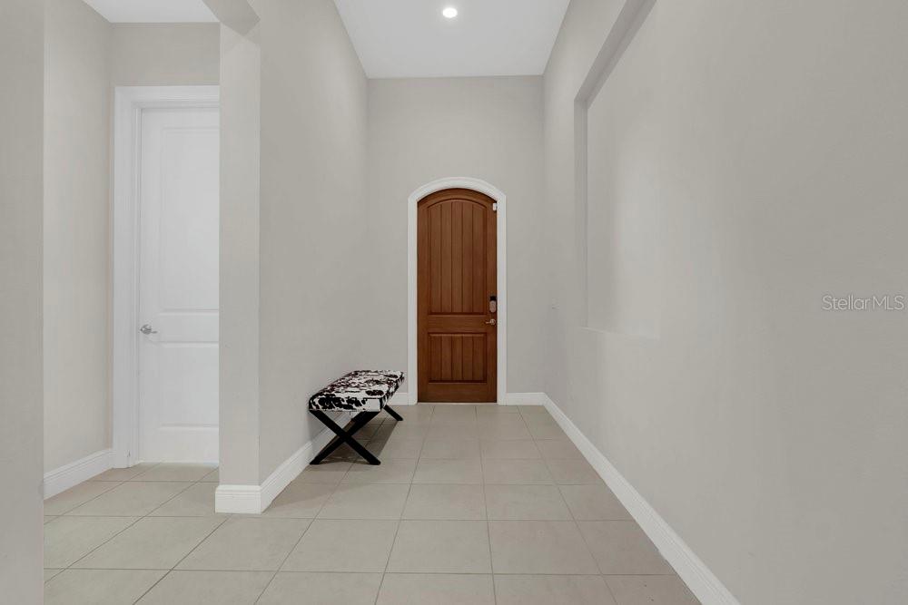 A tiled entryway features a white door, a wooden arched door, and a patterned bench — 15607 SYLVESTER PALM DRIVE, WINTER GARDEN, FL