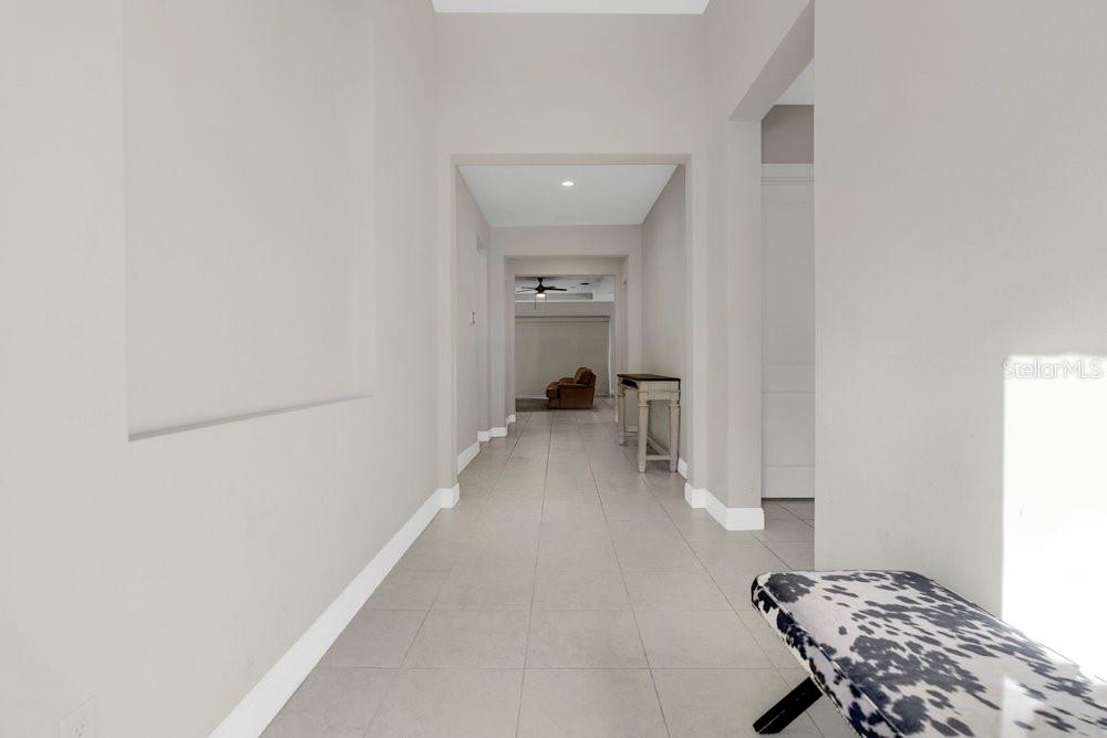 A long hallway with light tile flooring leads toward an open living area — 15607 SYLVESTER PALM DRIVE, WINTER GARDEN, FL