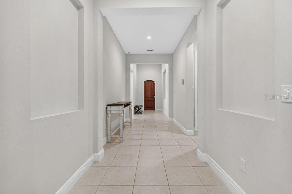 A tiled hallway features two recessed wall niches and a wooden console table — 15607 SYLVESTER PALM DRIVE, WINTER GARDEN, FL