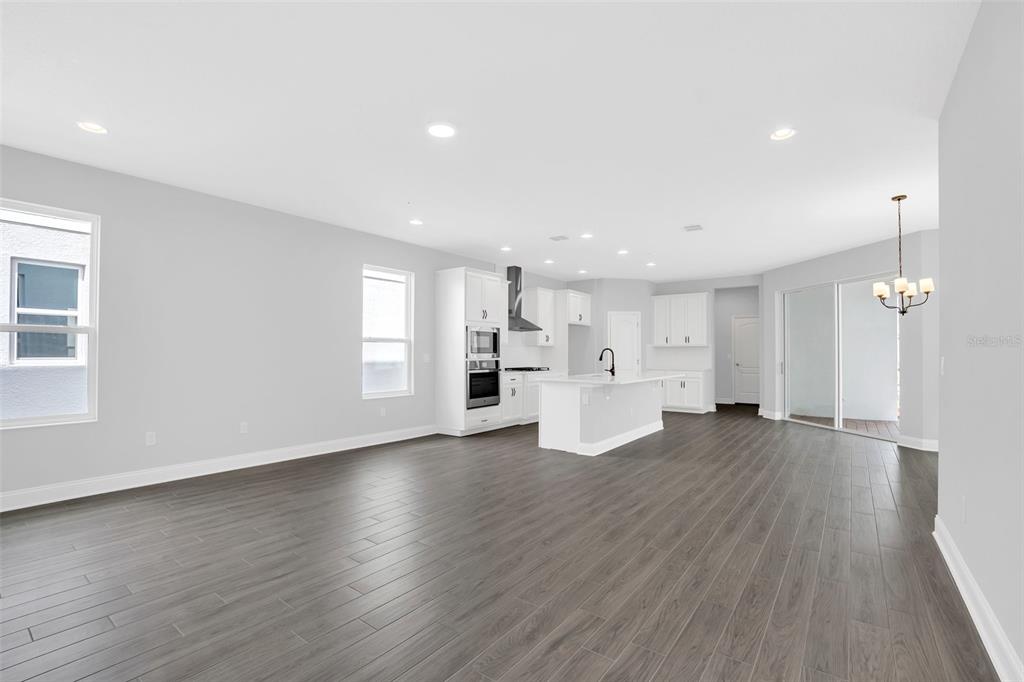 An open-concept kitchen and living area features white cabinetry, a central island, and dark flooring — 12743 BRODLOVE LANE, WINTER GARDEN, FL