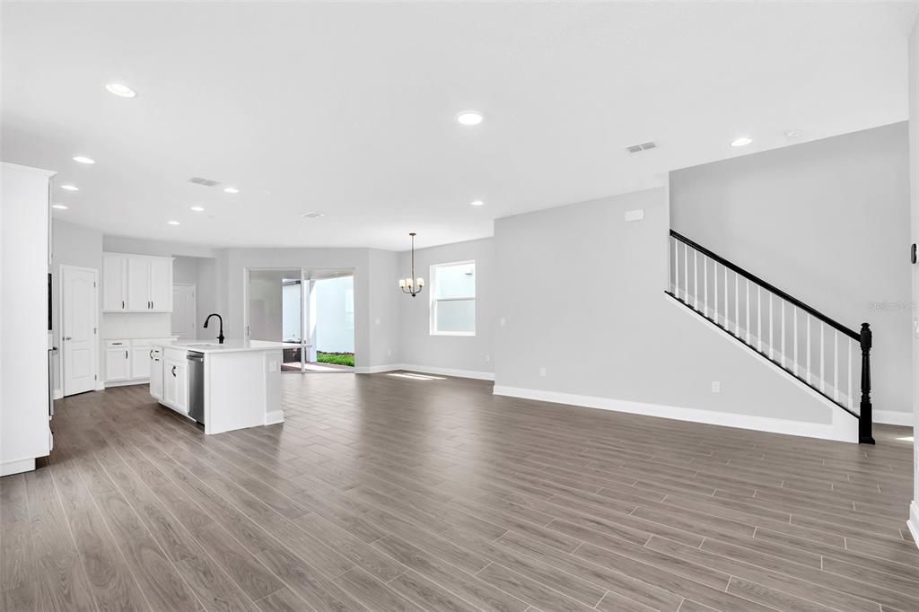 An open-concept kitchen and living area with light gray walls, white cabinetry, and wood-look flooring — 12743 BRODLOVE LANE, WINTER GARDEN, FL