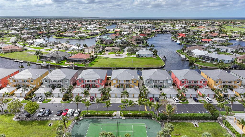 An aerial view shows a row of colorful townhouses next to a tennis court and canal — 2002 BAL HARBOR BOULEVARD UNIT 1822, PUNTA GORDA, FL