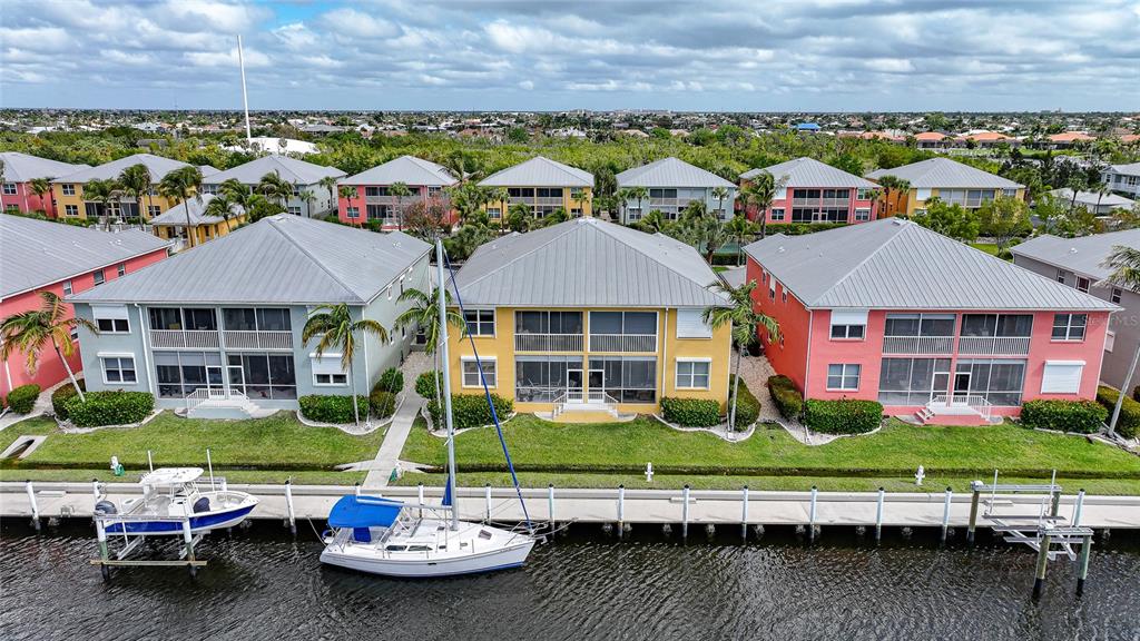An aerial view shows three colorful multi-story waterfront townhomes with boat slips along a canal — 2002 BAL HARBOR BOULEVARD UNIT 1822, PUNTA GORDA, FL