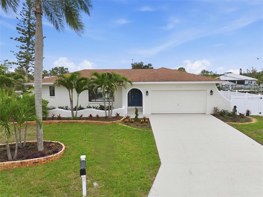 A single-story house with a white stucco exterior, a two-car garage, and a palm-lined lawn — 604 KINGSTON COURT, APOLLO BEACH, FL