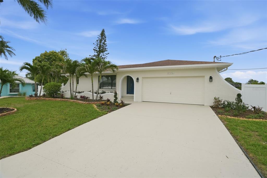 A single-story house with a white exterior, a two-car garage, and a palm-lined front yard — 604 KINGSTON COURT, APOLLO BEACH, FL