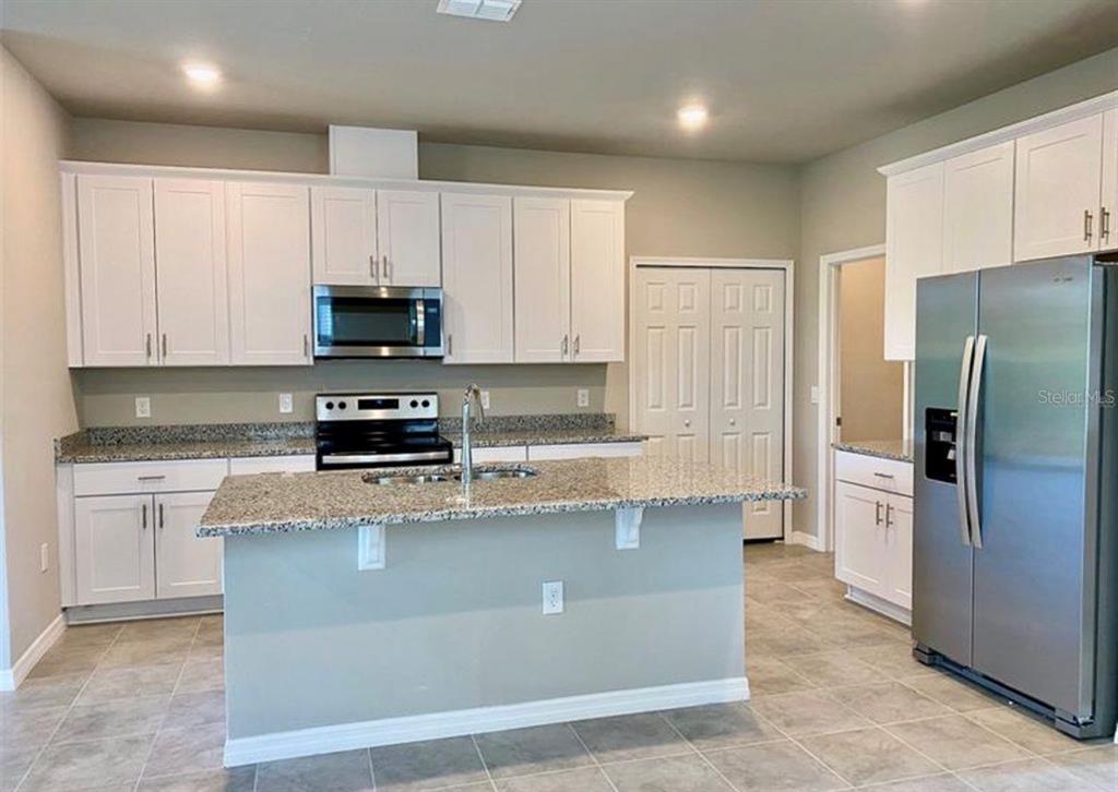 A kitchen with white cabinets, granite countertops, stainless steel appliances, and a central island — 2333 MYSTIC MAZE LANE, MINNEOLA, FL