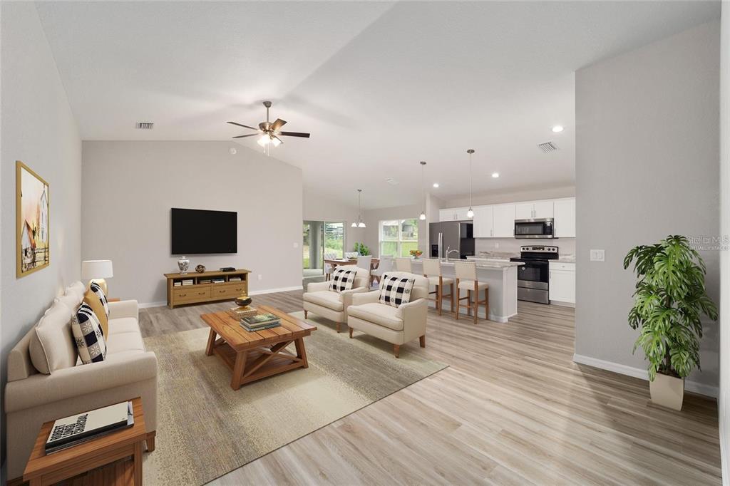 An open-concept living room and kitchen featuring light wood-look flooring and a vaulted ceiling — 16375 SE 80TH TERRACE, SUMMERFIELD, FL