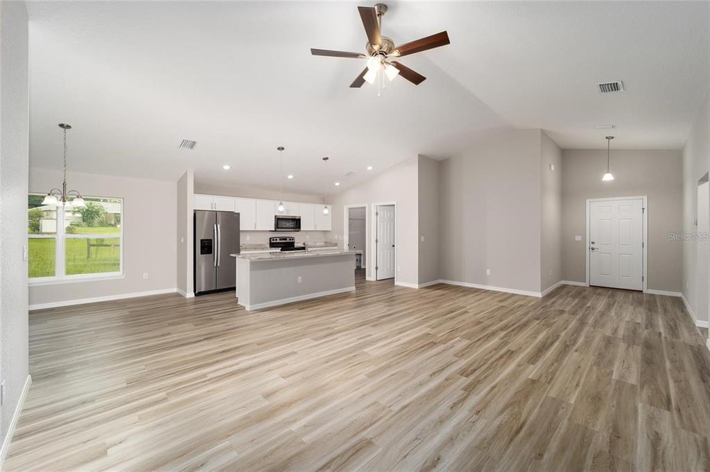 An open-concept living area features light wood-look flooring, a kitchen island, and a ceiling fan — 16375 SE 80TH TERRACE, SUMMERFIELD, FL