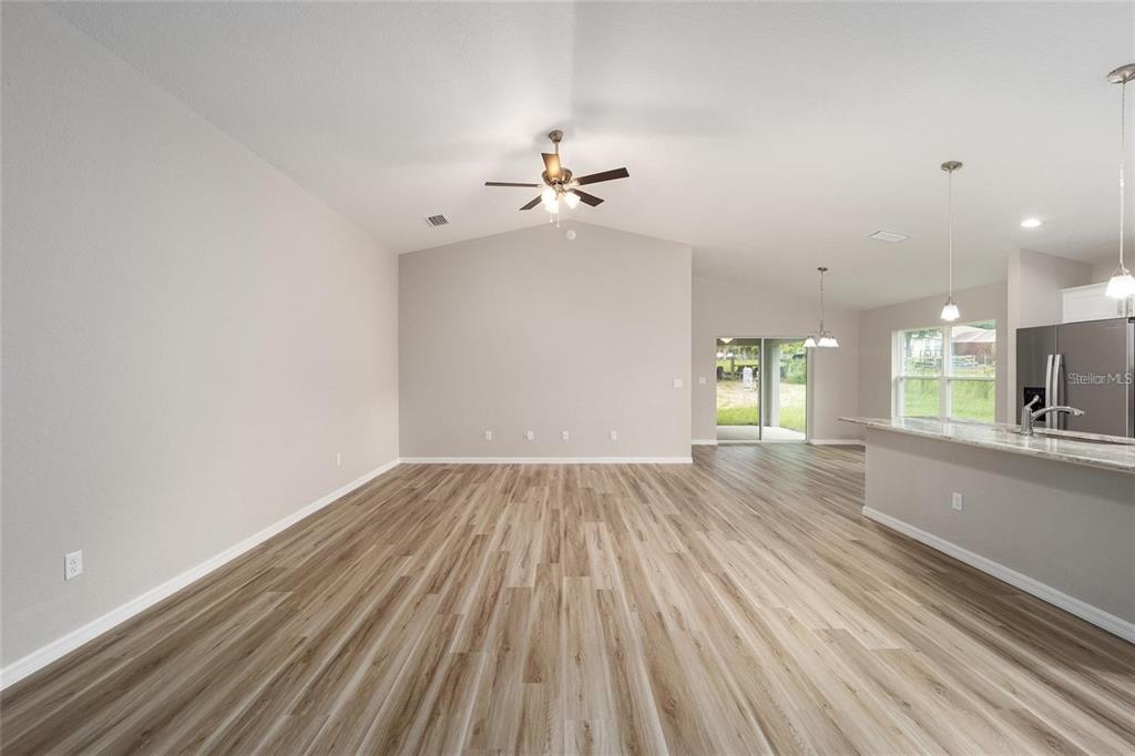 An open-concept living area features light wood-look flooring, a vaulted ceiling, and a kitchen island — 16375 SE 80TH TERRACE, SUMMERFIELD, FL