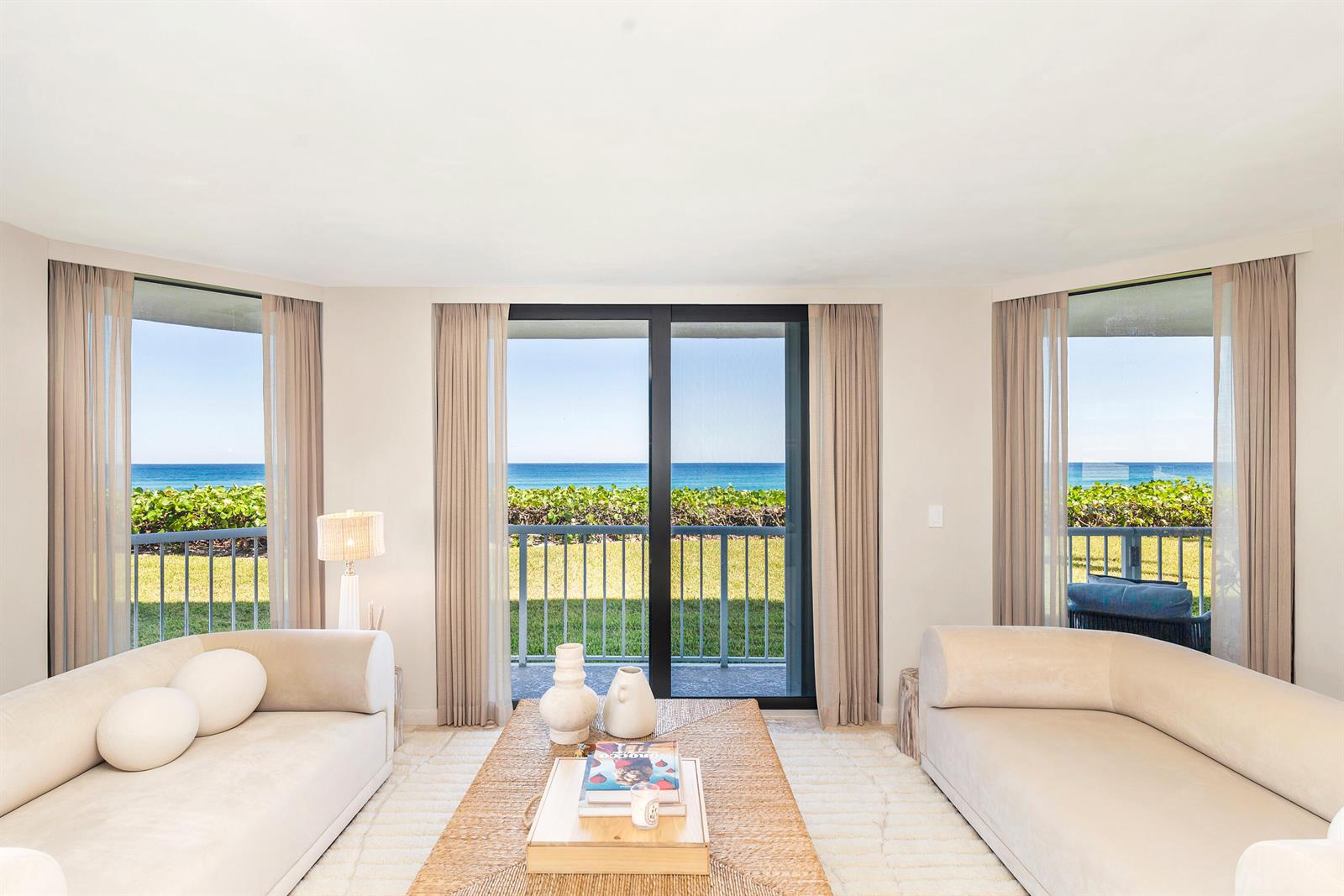 A living room with two beige sofas faces a sliding glass door overlooking the ocean — 3170 S Ocean Boulevard, Palm Beach FL 33480, PALM BEACH, FL
