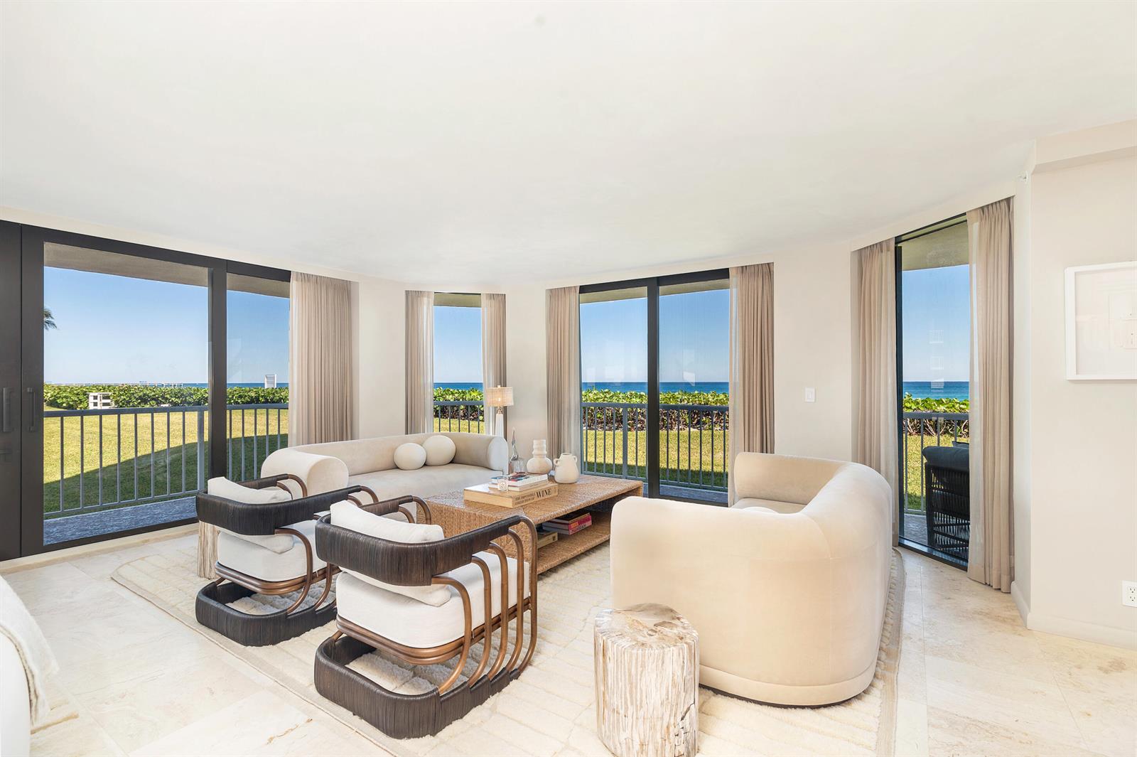 A bright living room features neutral furniture, a coffee table, and large windows overlooking the ocean — 3170 S Ocean Boulevard, Palm Beach FL 33480, PALM BEACH, FL