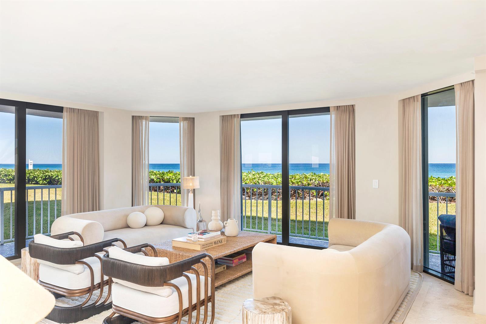 A living room with beige sofas, armchairs, and floor-to-ceiling windows overlooking the ocean — 3170 S Ocean Boulevard, Palm Beach FL 33480, PALM BEACH, FL