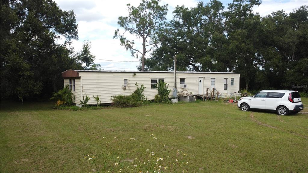 A single-story mobile home sits on a grassy lot with a white SUV parked nearby — 17281 SE 130TH, WEIRSDALE, FL
