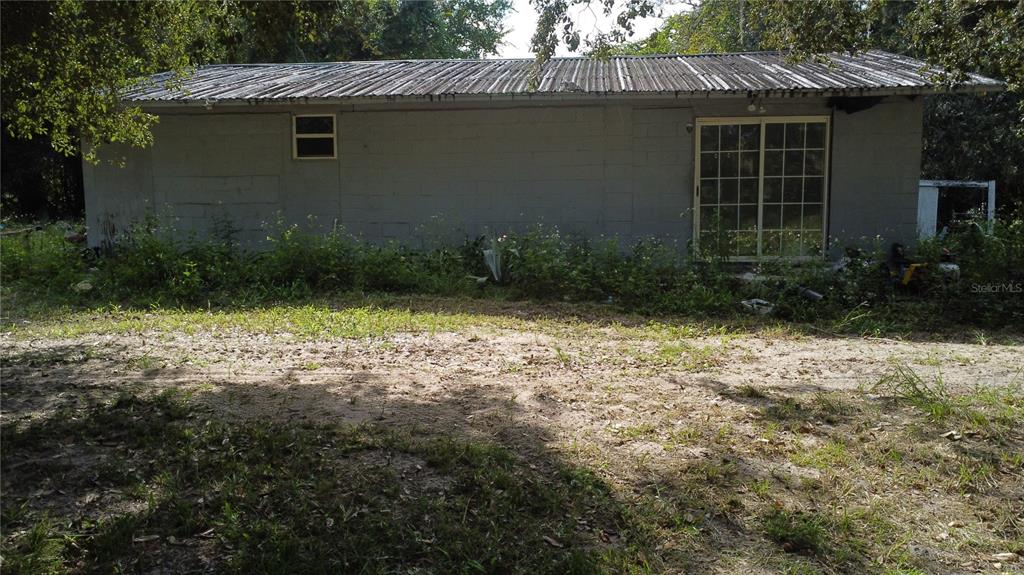 The exterior of a gray concrete block building features a metal roof and sliding glass doors — 17281 SE 130TH, WEIRSDALE, FL