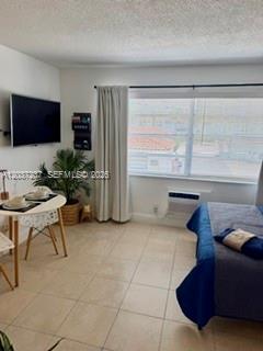 A furnished bedroom features a wall-mounted television, a small dining table, and a window — 17 NE 2nd Ave # 203, Dania Beach FL 33004, DANIA BEACH, FL