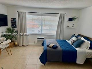 A bedroom features a bed with blue bedding, a window with curtains, and a small desk — 17 NE 2nd Ave # 203, Dania Beach FL 33004, DANIA BEACH, FL