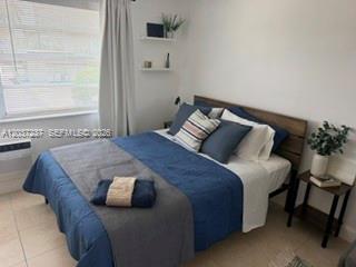 A bedroom features a bed with blue bedding, a wooden headboard, and two wall-mounted shelves — 17 NE 2nd Ave # 203, Dania Beach FL 33004, DANIA BEACH, FL
