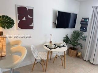 A small dining area features a round white table, two chairs, and a wall-mounted television — 17 NE 2nd Ave # 203, Dania Beach FL 33004, DANIA BEACH, FL