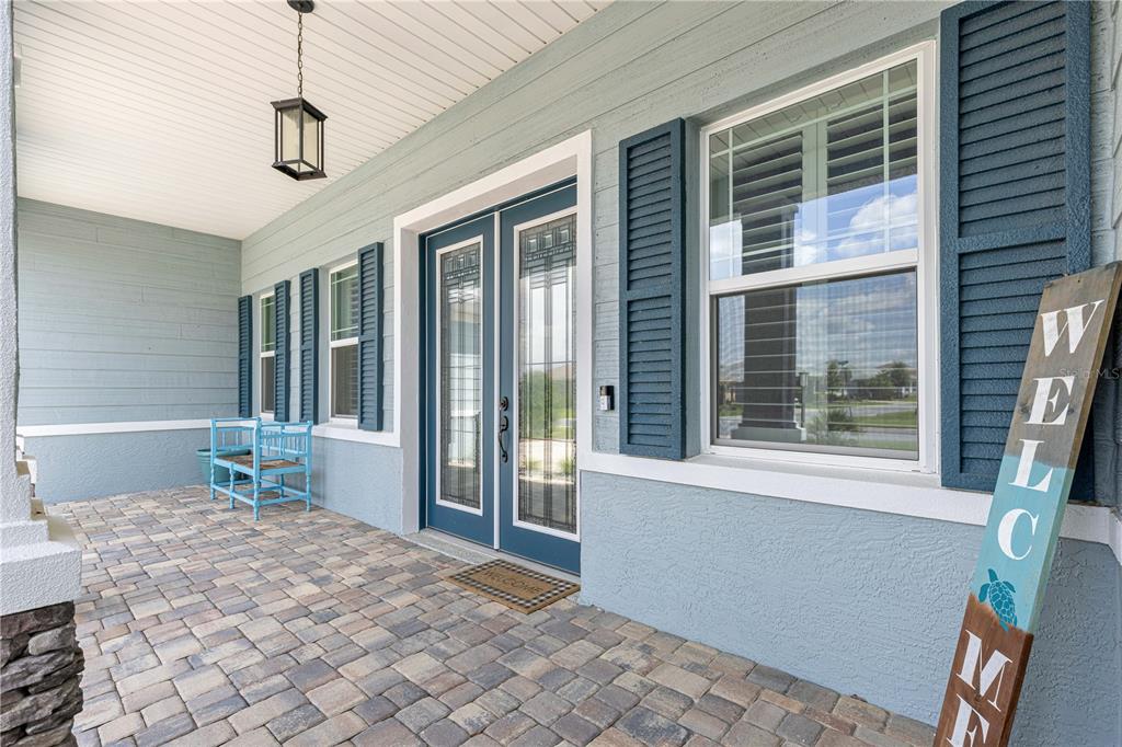 A covered front porch features a paver floor, blue siding, double doors, and a welcome sign — 9791 SW 82ND STREET ROAD, OCALA, FL