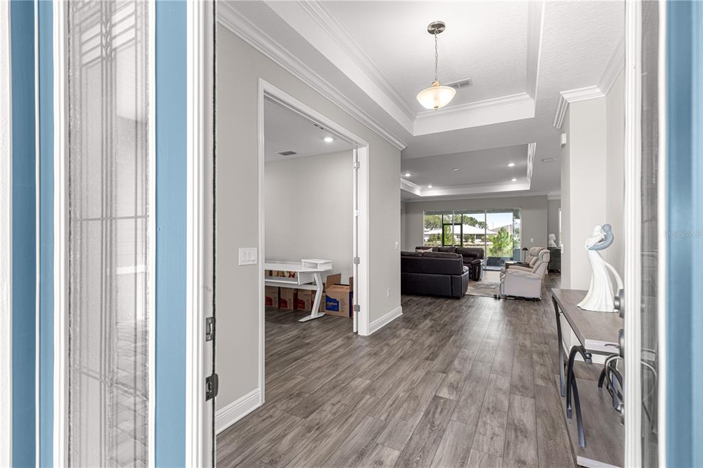A view from a doorway into a home with gray wood-look flooring and tray ceilings — 9791 SW 82ND STREET ROAD, OCALA, FL