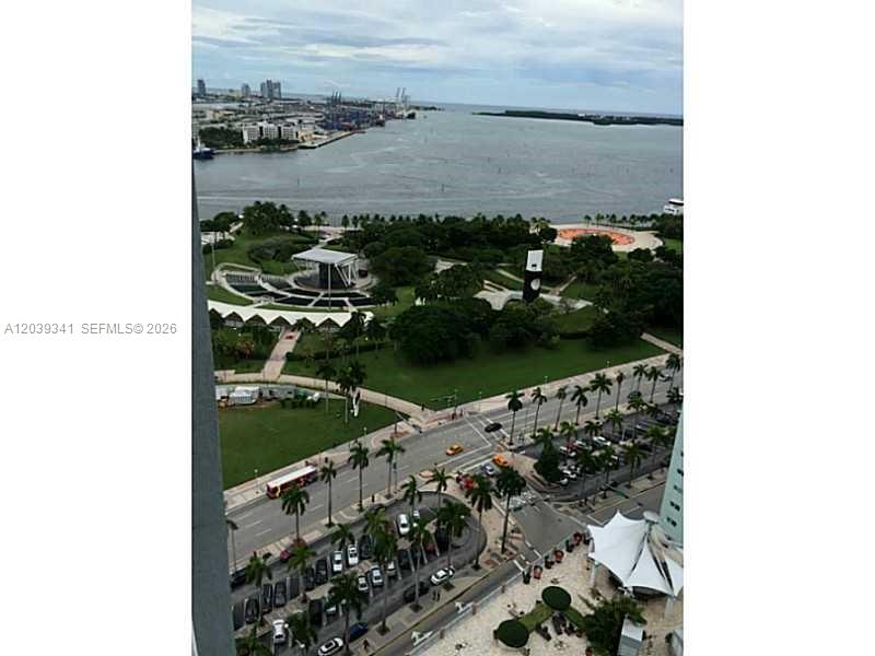 An elevated view shows a city park, a waterfront, and a parking lot with palm trees — MIAMI, FL