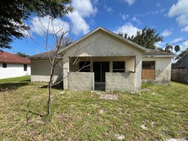 Exterior view of a single-story house with a covered porch and a boarded-up window — 265 SE TWIG AVENUE, PORT ST LUCIE, FL