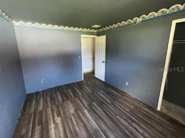 An empty room with dark blue walls, wood-look flooring, and a white interior door — 265 SE TWIG AVENUE, PORT ST LUCIE, FL