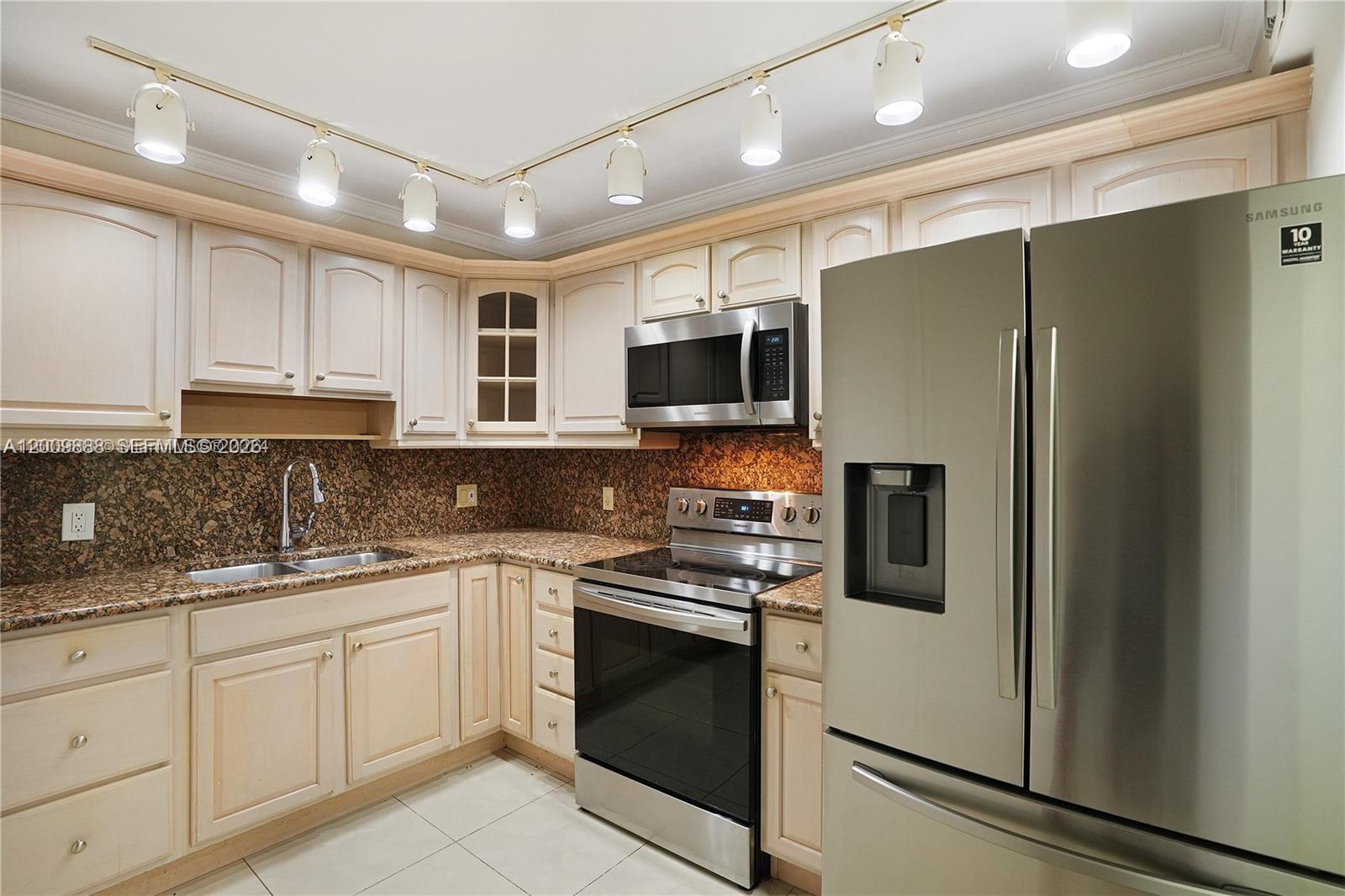 A kitchen features light wood cabinets, granite countertops, stainless steel appliances, and track lighting — 3800 S Ocean Dr # 414, Hollywood FL 33019, HOLLYWOOD, FL