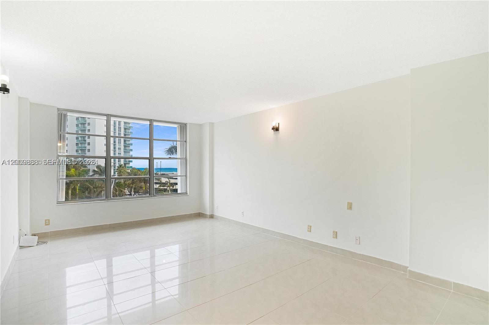 An empty room with white walls, tile flooring, and large windows overlooking the ocean — 3800 S Ocean Dr # 414, Hollywood FL 33019, HOLLYWOOD, FL