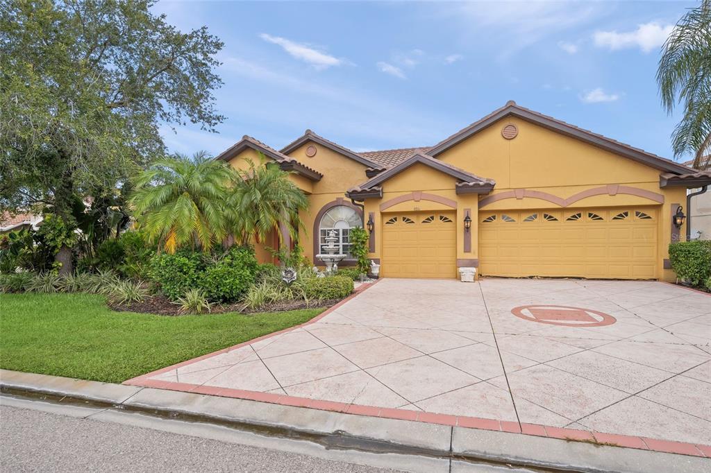 A single-story house with a yellow stucco exterior, a three-car garage, and a paved driveway — 8214 BARTON FARMS BOULEVARD, SARASOTA, FL