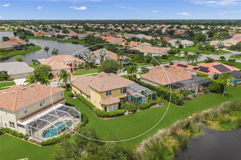 An aerial view of a yellow stucco house with a tiled roof near a lake — 8214 BARTON FARMS BOULEVARD, SARASOTA, FL