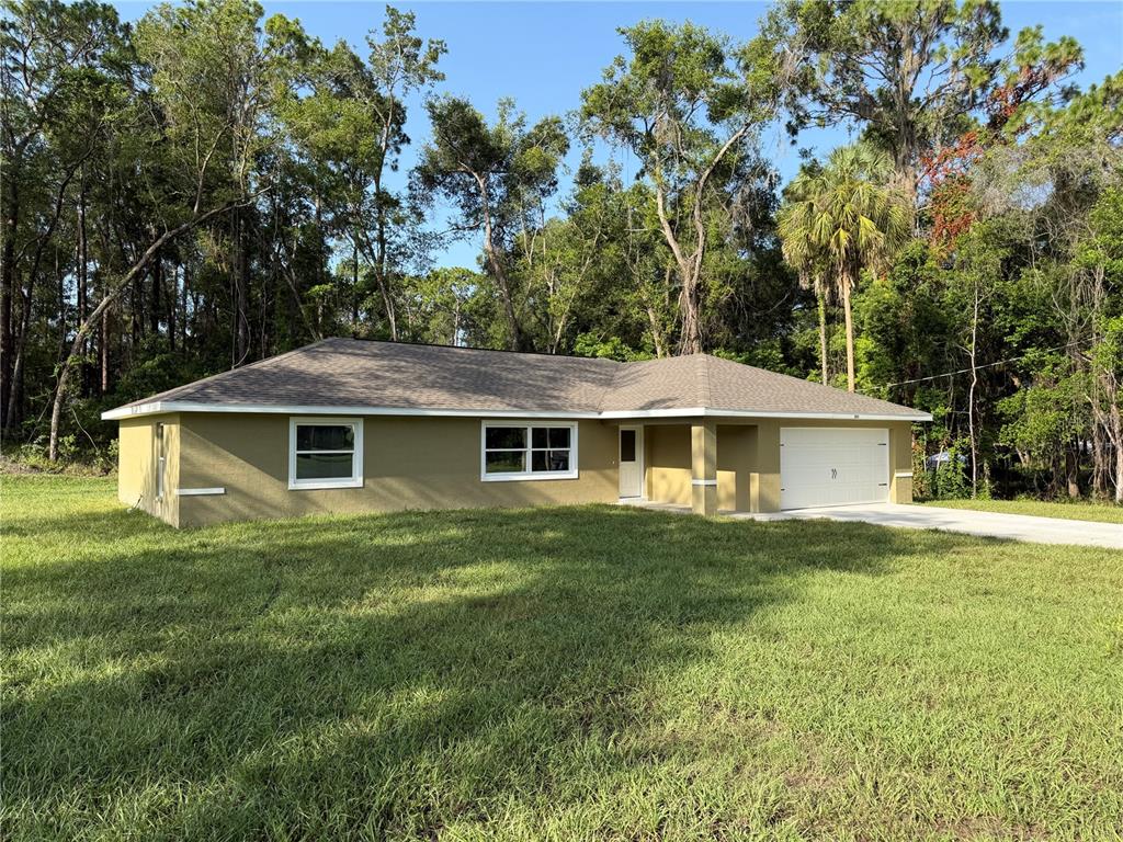 A single-story house with a tan exterior, a two-car garage, and a large grassy yard — 205 W INVERNESS BOULEVARD, INVERNESS, FL
