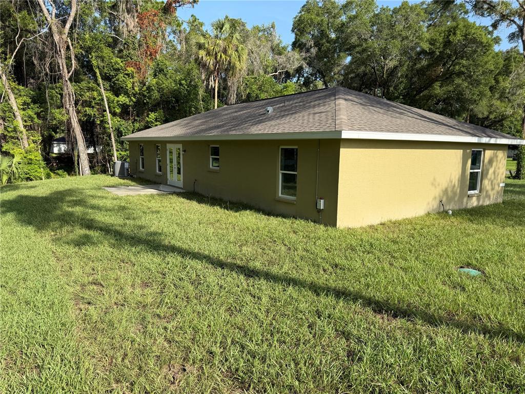 A tan, single-story house with a hip roof sits on a grassy, wooded lot — 205 W INVERNESS BOULEVARD, INVERNESS, FL