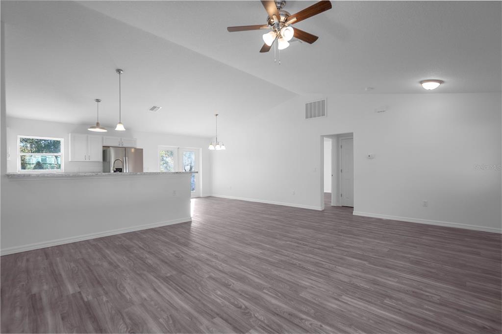 An open-concept living and dining area features white walls, gray wood-look flooring, and a kitchen — 205 W INVERNESS BOULEVARD, INVERNESS, FL