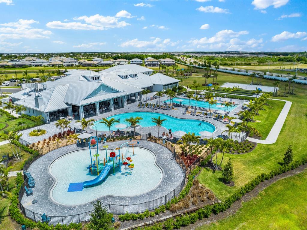 An aerial view shows a community clubhouse with a large pool and a children's splash pad — 15949 CLEAR SKIES PLACE, BRADENTON, FL