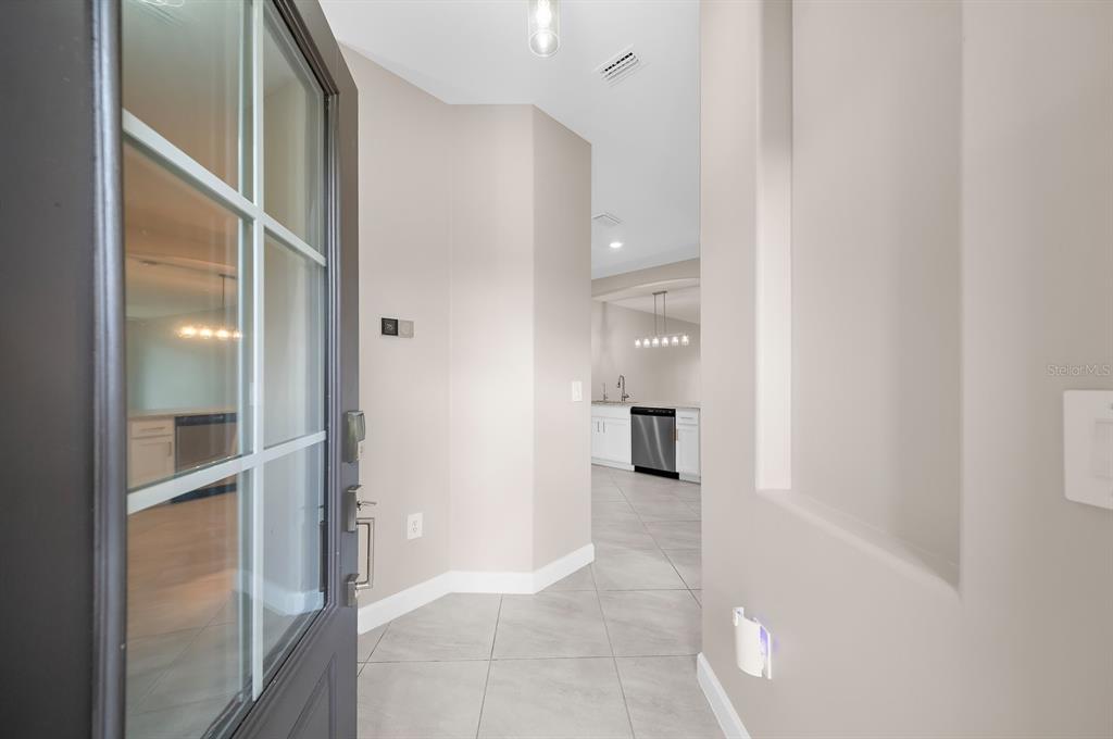 A view from an open front door into a tiled entryway leading toward a kitchen — 15949 CLEAR SKIES PLACE, BRADENTON, FL