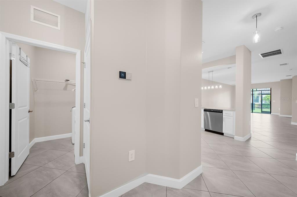 A view from a hallway into a kitchen with tile flooring and a laundry closet — 15949 CLEAR SKIES PLACE, BRADENTON, FL