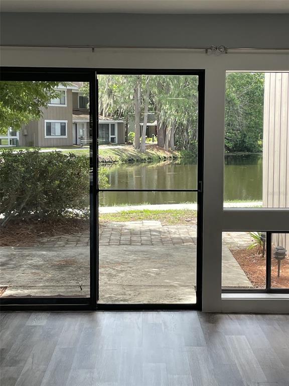 A view through a sliding glass door shows a patio, a pond, and trees — 5932 PEREGRINE AVENUE UNIT 22D, ORLANDO, FL