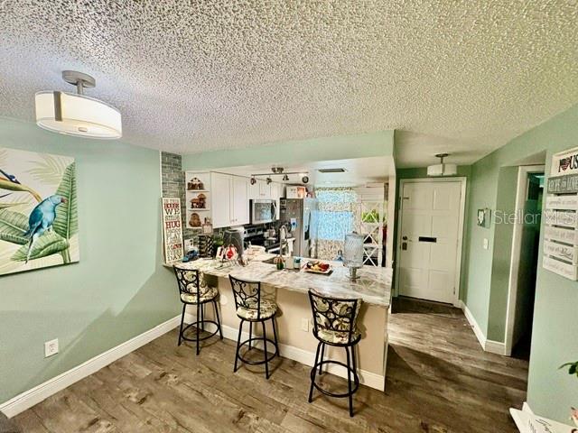 A kitchen features white cabinets, stainless steel appliances, and a stone-topped island with seating — 4247 SHELDON PLACE UNIT 1, NEW PORT RICHEY, FL