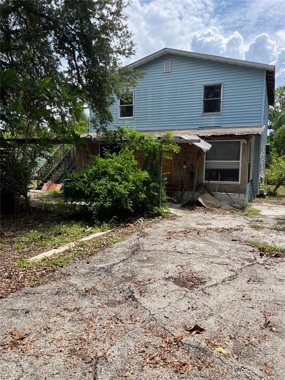 A two-story light blue house with a cracked concrete driveway and overgrown vegetation — 903 ANDERSON ROAD, NOKOMIS, FL