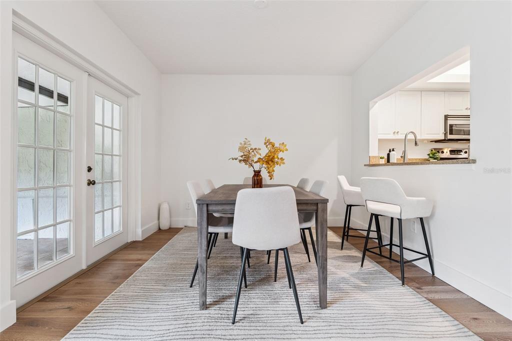A dining area with a wooden table, white chairs, and a rug near a kitchen pass-through — 1994 KENASTON ROAD UNIT 1994, MAITLAND, FL