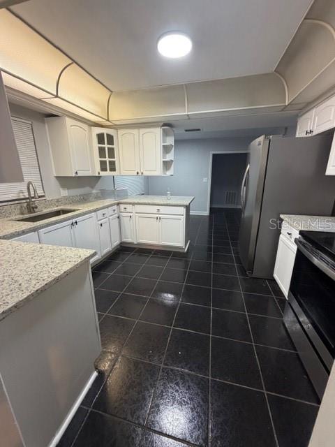 A kitchen features white cabinets, granite countertops, and dark tile flooring — 7109 OELSNER STREET, NEW PORT RICHEY, FL
