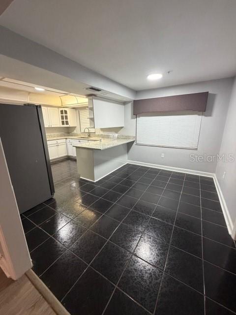 A kitchen with white cabinets, a peninsula, and dark tiled flooring — 7109 OELSNER STREET, NEW PORT RICHEY, FL