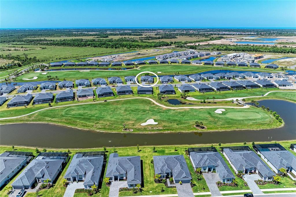 An aerial view shows a residential neighborhood with houses surrounding a golf course and lake — 17215 ALBATROSS ROAD, VENICE, FL