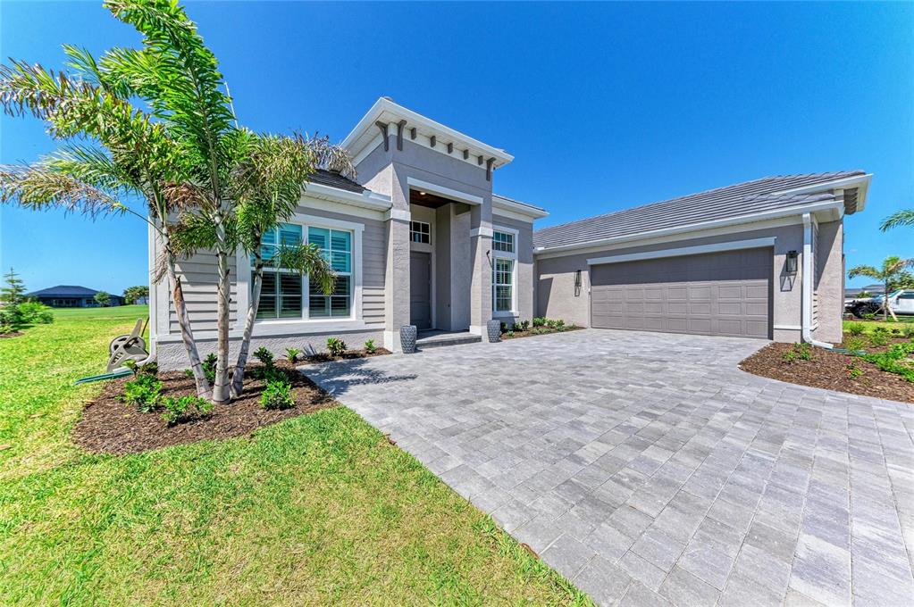 A single-story house with a gray exterior, a paved driveway, and a palm tree — 17215 ALBATROSS ROAD, VENICE, FL