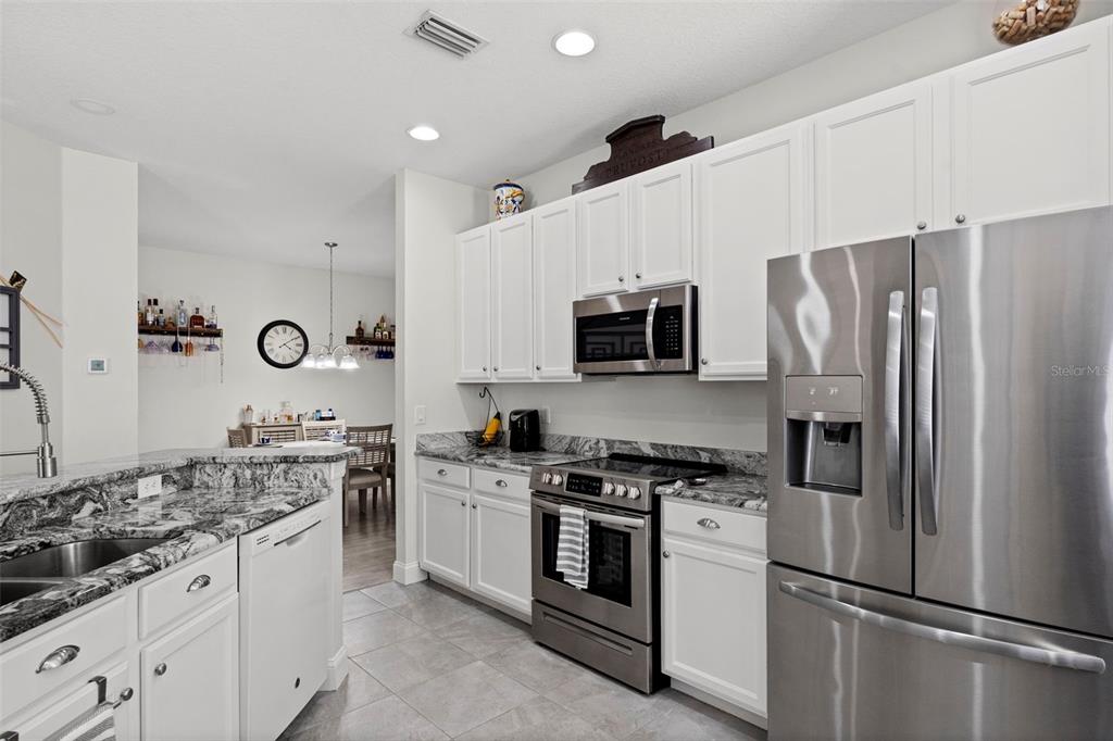 A kitchen features white cabinets, granite countertops, stainless steel appliances, and tile flooring — 10818 ASHFORD OAKS DRIVE, TAMPA, FL